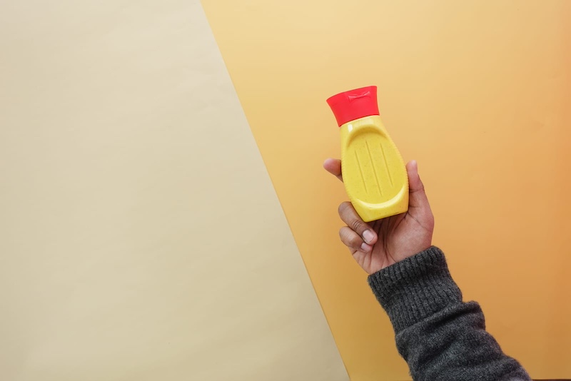 person holding bottle of mustard